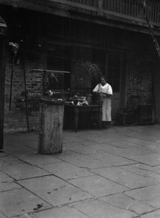 Woman working in a courtyard, New Orleans, between 1920 and 1926. Creator: Arnold Genthe