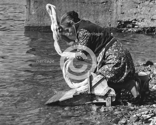 Woman washing clothes in a river, Portugal, 1973. 