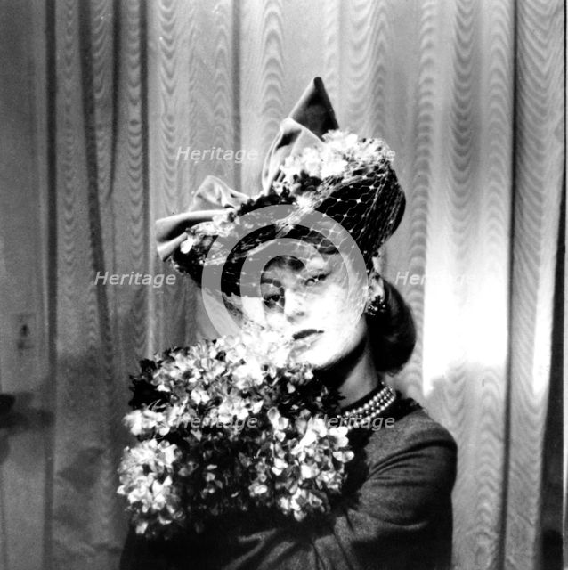Woman wearing a hat with a veil, holding a bouquet of flowers, Paris, 1943. Artist: Unknown