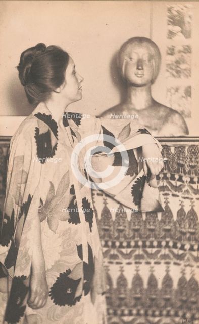 Woman wearing a kimono, standing, looking at a sculpted bust, c1900. Creator: Eva Watson-Schutze.