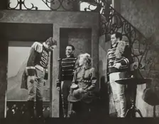 Woman with hat on knee talking to three men, 1938. Creator: Unknown