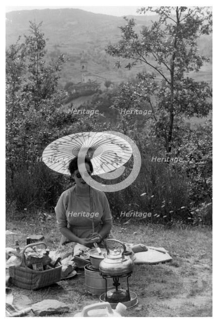 Woman under a parasol having a picnic, c1950-1969(?). Artist: Unknown