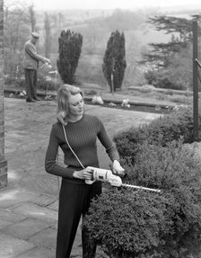 Woman using Stanley electric garden shears, 1965. Creator: Michael Walters