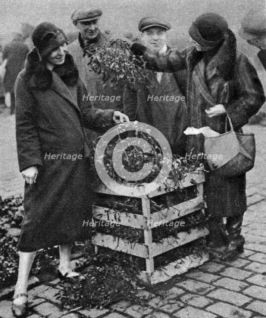 Women choosing bunches of mistletoe, Caledonian Market, London, 1926-1927. Artist: Unknown