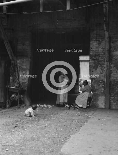 Women and children in a courtyard, New Orleans, between 1920 and 1926. Creator: Arnold Genthe.