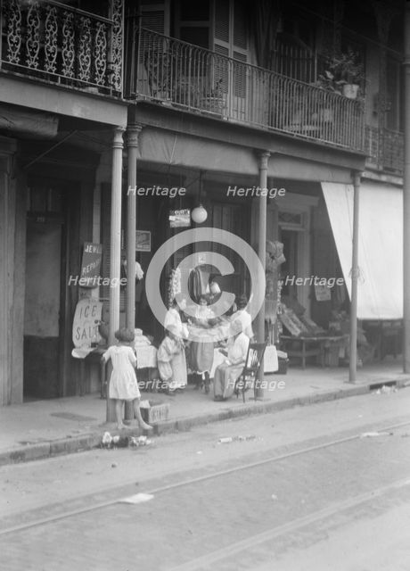 Women and children standing on a covered sidewalk, New Orleans, between 1920 and 1926. Creator: Arnold Genthe.