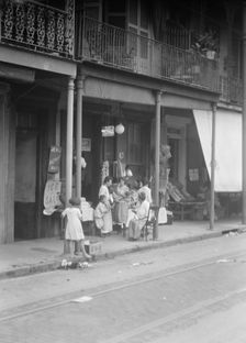 Women and children standing on a covered sidewalk, New Orleans, between 1920 and 1926. Creator: Arnold Genthe