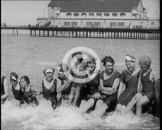 Women and Children Sitting on a Groyne, Splashing With Their Feet on a British Beach, 1920. Creator: British Pathe Ltd.