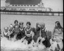 Women and Children Sitting on a Groyne, Splashing With Their Feet on a British Beach, 1920. Creator: British Pathe Ltd
