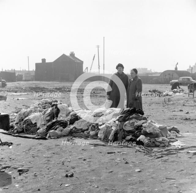 Women standing by a pile of clothes at Rathbone Street Market, London, 1959. Artist: Henry Grant