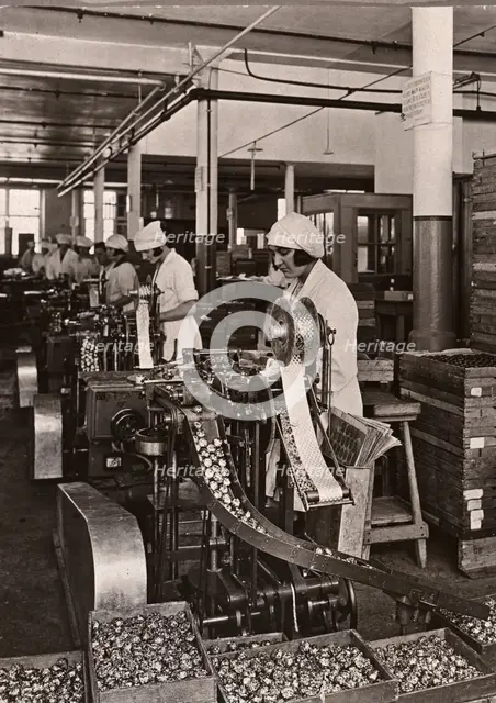 Women work on foiling machines, Rowntree factory, York, Yorkshire, 1933. Artist: Unknown