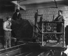 Wooden box industry - Mrs. Graham inspecting log on machinery with two workmen standing by, c1910. Creator: Frances Benjamin Johnston