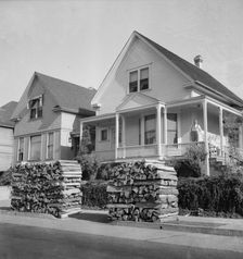 Woodpiles along the street are a characteristic of Portland, Oregon, 1939. Creator: Dorothea Lange