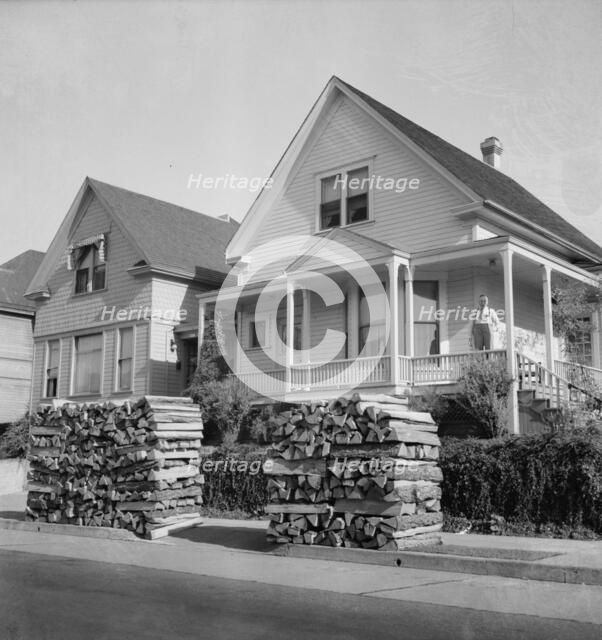 Woodpiles along the street are a characteristic of Portland, Oregon, 1939. Creator: Dorothea Lange.