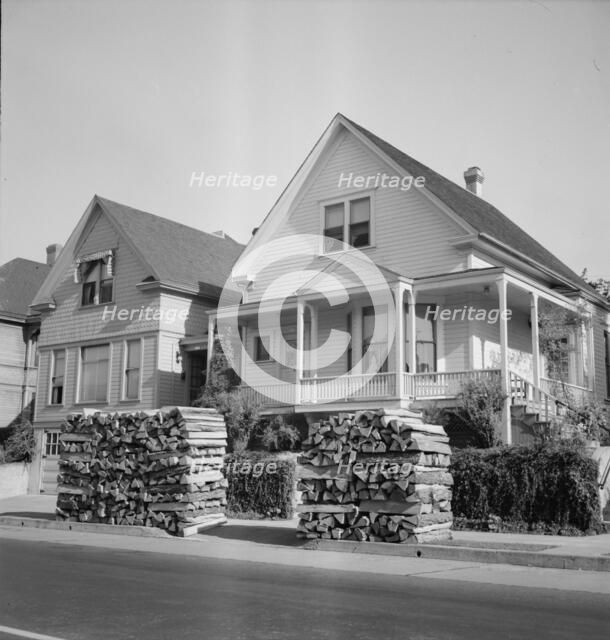 Woodpiles along the street are a characteristic of Portland, Oregon, 1939. Creator: Dorothea Lange.