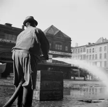 Workmen from the sanitary department flushing the street in front of the Fulton..., New York, 1943. Creator: Gordon Parks