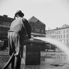 Workmen from the sanitary department flushing the street in front of the Fulton..., New York, 1943. Creator: Gordon Parks