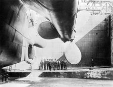 Workmen standing under one of the propellors of the Titanic, 31 May, 1911. Creator: English Photographer (20th Century)