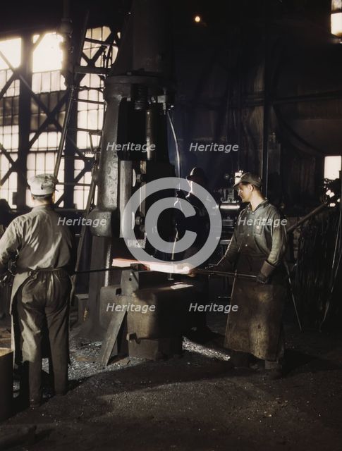 Working with a small steam drop hammer, blacksmith shop, Santa Fe RR shops, Topeka, Kansas, 1943. Creator: Jack Delano.