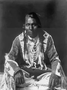Wades in Water, Piegan Indian, full-length portrait, seated on floor, facing front..., c1910. Creator: Edward Sheriff Curtis