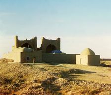 Walled adobe structure with domes and arches in desert area, with man posed..., between 1905-1915. Creator: Sergey Mikhaylovich Prokudin-Gorsky