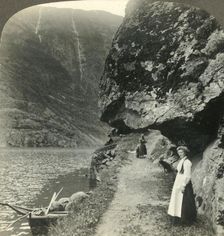 Where the road creeps under the jutting cliffs by the waters of the Nerofjord, Norway c1905. Creator: Unknown