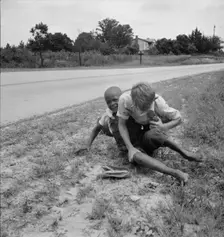 White and Negro boy wrestling by side of road, Person County, North Carolina, 1939. Creator: Dorothea Lange