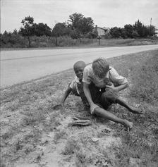 White and Negro boy wrestling by side of road, Person County, North Carolina, 1939. Creator: Dorothea Lange