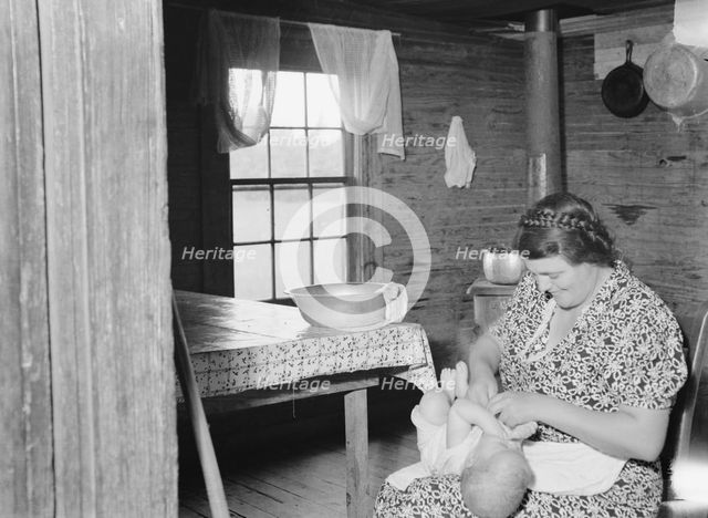 Wife of tobacco sharecropper bathing baby in kitchen, Person County, North Carolina, 1939. Creator: Dorothea Lange.