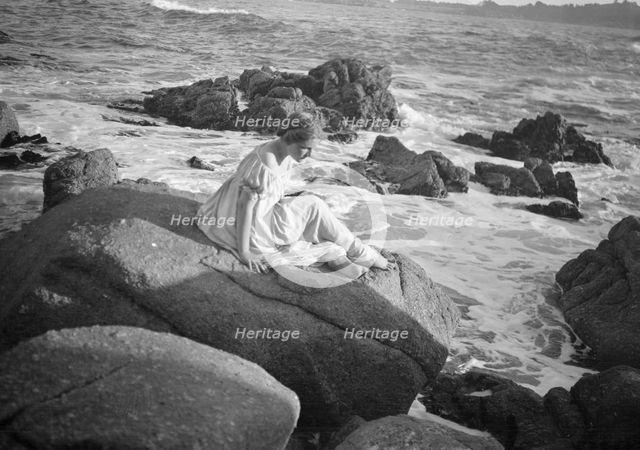 Wilson, Helen, Mrs., seated on rocks at the beach, between 1906 and 1928. Creator: Arnold Genthe.