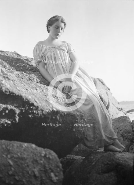 Wilson, Helen, Mrs., seated on rocks at the beach, between 1906 and 1928. Creator: Arnold Genthe.