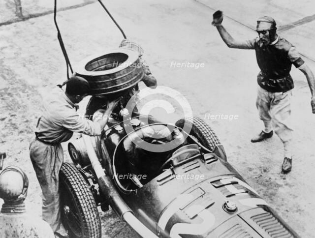 Tazio Nuvolari waiting for his car to be refuelled, c1930s(?). Artist: Unknown