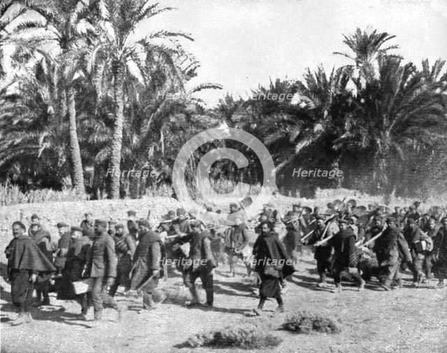 'Tandis que.; Voici des prisonniers allemands traversant une riante oasis algerienne pour..., 1917 Creator: Unknown.