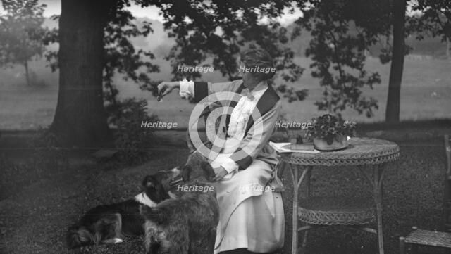 Tarbell, Ida, Miss, with dogs, seated outdoors, 1912 or 1913. Creator: Arnold Genthe.