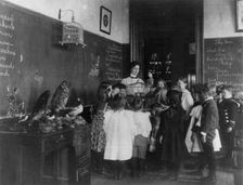Teacher and group of grade school children standing around bird cage and..., Washington DC, (1899?). Creator: Frances Benjamin Johnston