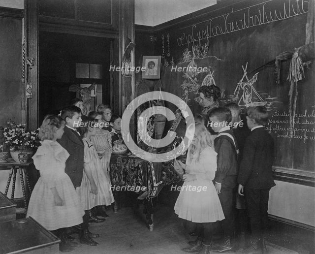 Teacher showing students Native American handicrafts at a school in Washington, D.C., (1899?). Creator: Frances Benjamin Johnston.