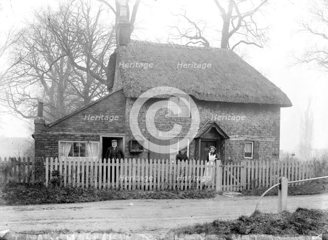 Thatched cottage with the inhabitants standing in the front garden, Uffington, Oxfordshire, 1916. Artist: Henry Taunt