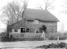 Thatched cottage with the inhabitants standing in the front garden, Uffington, Oxfordshire, 1916. Artist: Henry Taunt