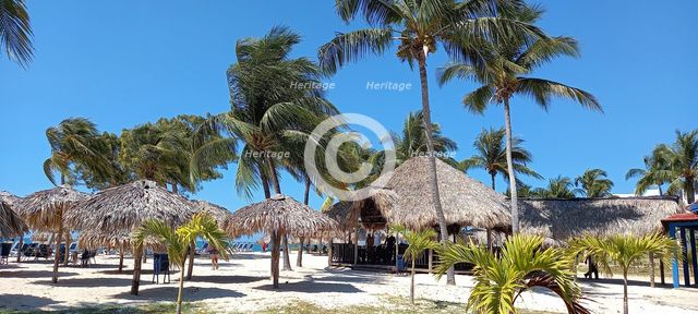 Thatched umbrellas and restaurant at the beach resort of Playa Ancon, south of Trinidad, Cuba, 2024. Creator: Ethel Davies.