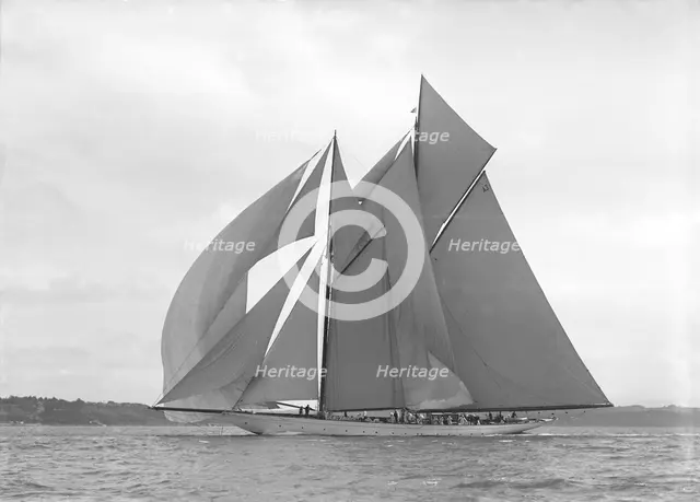 The 250 ton schooner 'Germania' sails downwind under spinnaker, 1911. Creator: Kirk & Sons of Cowes.