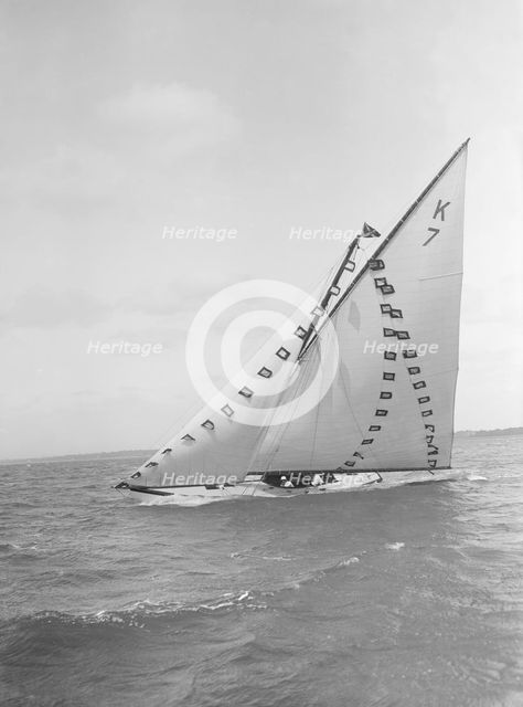 The 7 Metre 'Ginerva' (K7) under sail with prize flags, 1912. Creator: Kirk & Sons of Cowes.