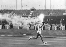 The Olympic flame entering the Olympic Stadium, Tokyo, 10 October 1964. Creator: Unknown