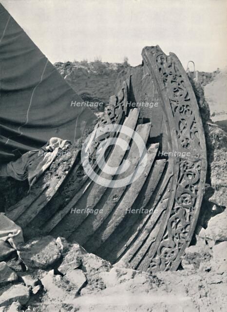 'The Oseberg ship in the mound, showing the carving on stem and railing', 1935. Artist: Unknown.