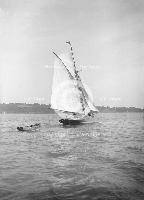 The cutter 'Citara' under sail and towing tender, 1911. Creator: Kirk & Sons of Cowes.