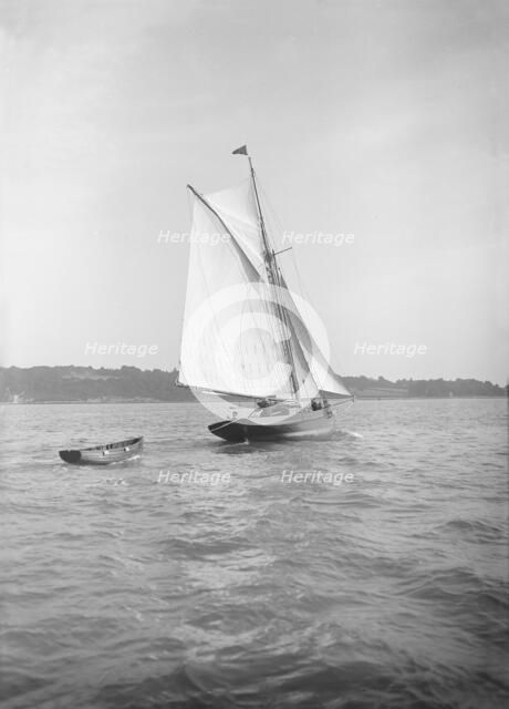 The cutter 'Citara' under sail and towing tender, 1911. Creator: Kirk & Sons of Cowes.