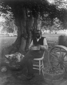 The cook at Marshall Hall, seated outdoors, shelling peas?, c1890. Creator: Frances Benjamin Johnston