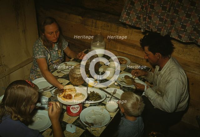 The Faro Caudill family eating dinner in their dugout, Pie Town, New Mexico, 1940. Creator: Russell Lee.