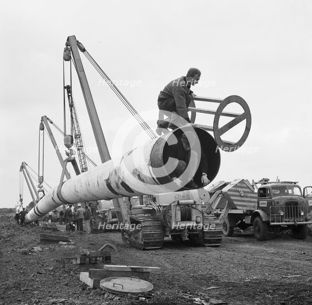 The Fens gas pipeline being lifted by a row of Caterpillar 583 pipelayers, Norfolk, 20/09/1967. Creator: John Laing plc.