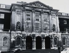 The front entrance of Guy's Hospital, with statues of Aesculapius and Hygieia above the arches. Creator: Unknown