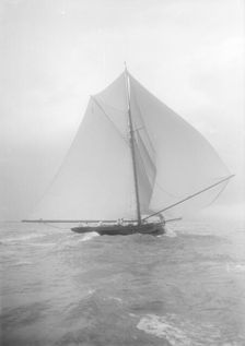 The gaff rigged cutter Bloodhound sailing downwind under spinnaker, August 1912. Creator: Kirk & Sons of Cowes